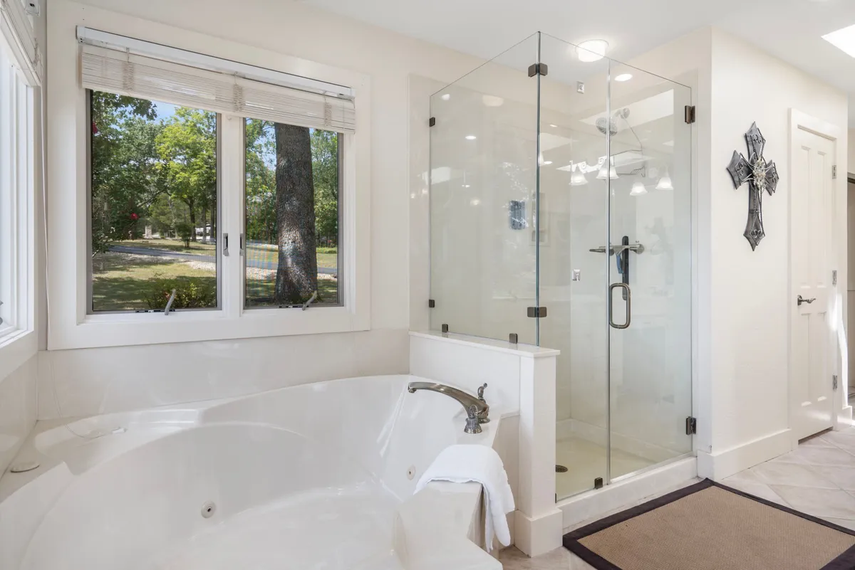 A spa-inspired bathroom featuring a freestanding bathtub, a glass-enclosed shower, and a window that lets in natural light. The serene setting is ideal for soaking after a day of adventure or enjoying a calming morning routine.