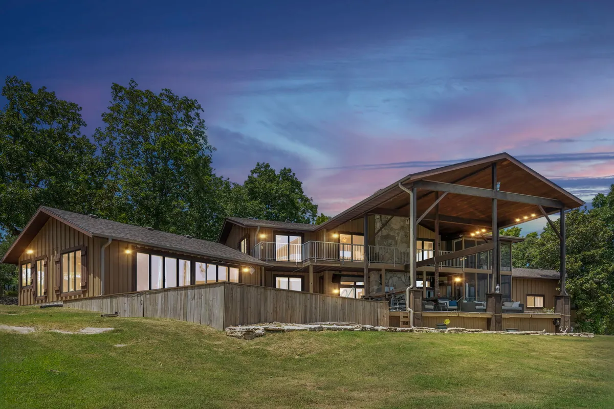 A striking exterior view of the home’s large windows, exposed wooden beams, and a spacious deck area. The ambiance is inviting and tranquil, hinting at social gatherings, sunset watching, and alfresco dining.