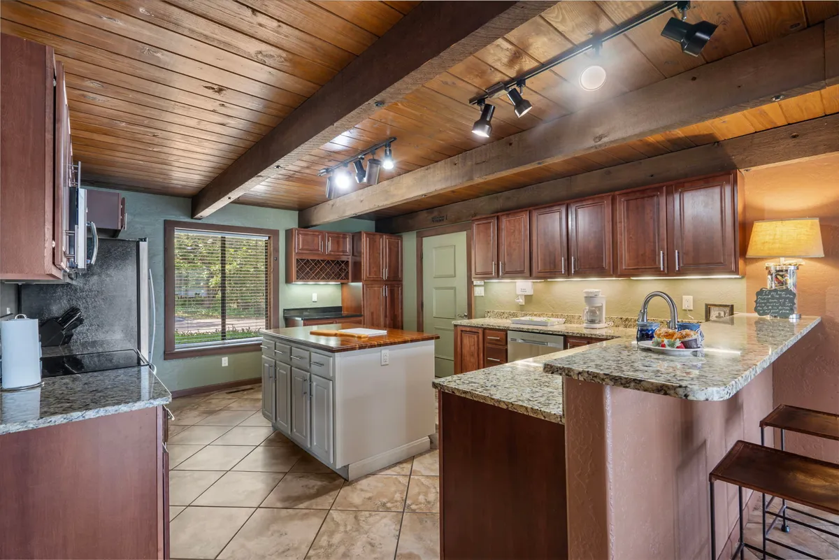 A bright, modern kitchen with granite countertops, wooden beams, stainless steel appliances, and a spacious island. The design is both functional and inviting, ideal for preparing fresh catches or hosting group meals.