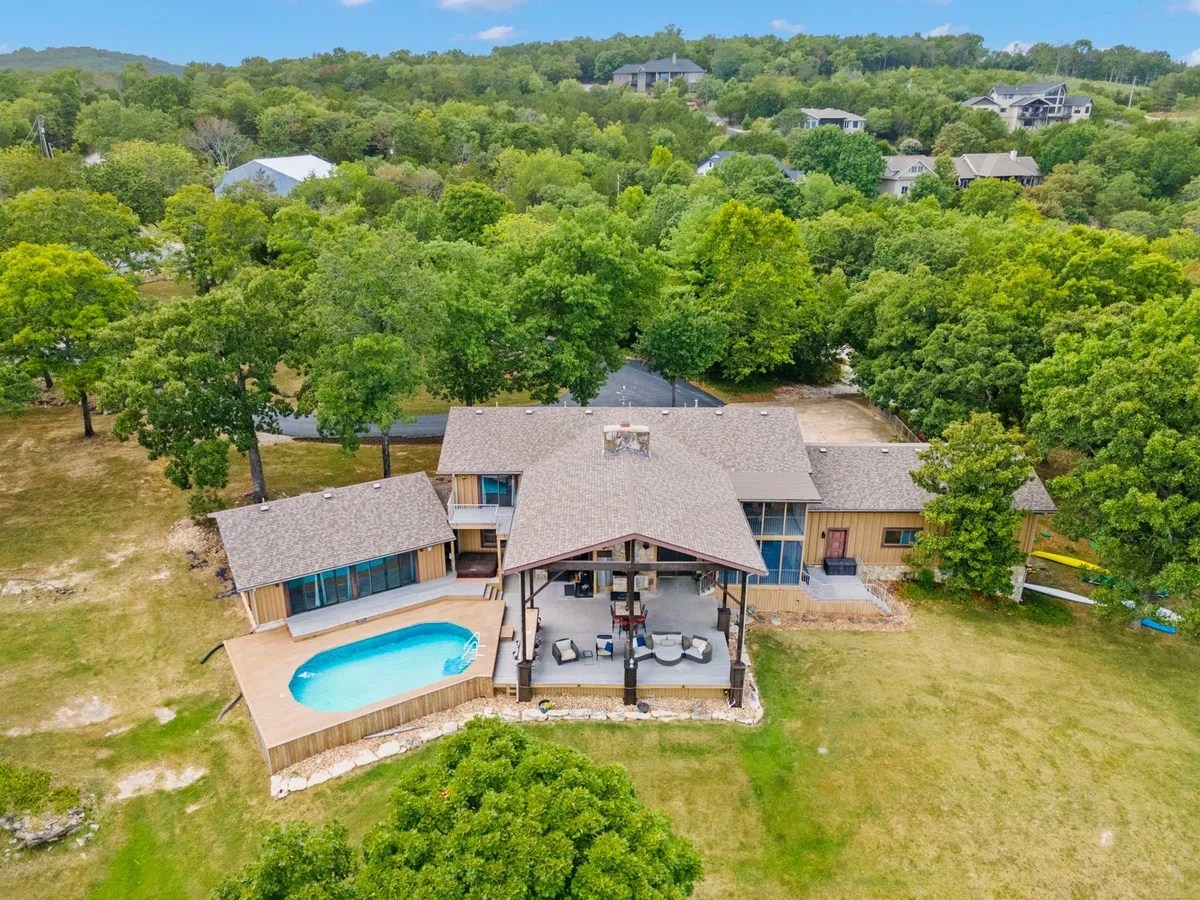 This exterior shot features a sparkling swimming pool surrounded by lush greenery and an inviting outdoor seating area. The tranquil atmosphere is enhanced by the surrounding trees and open sky, offering a sense of privacy and luxury. The pool is clearly the focal point, ideal for relaxation or family fun.