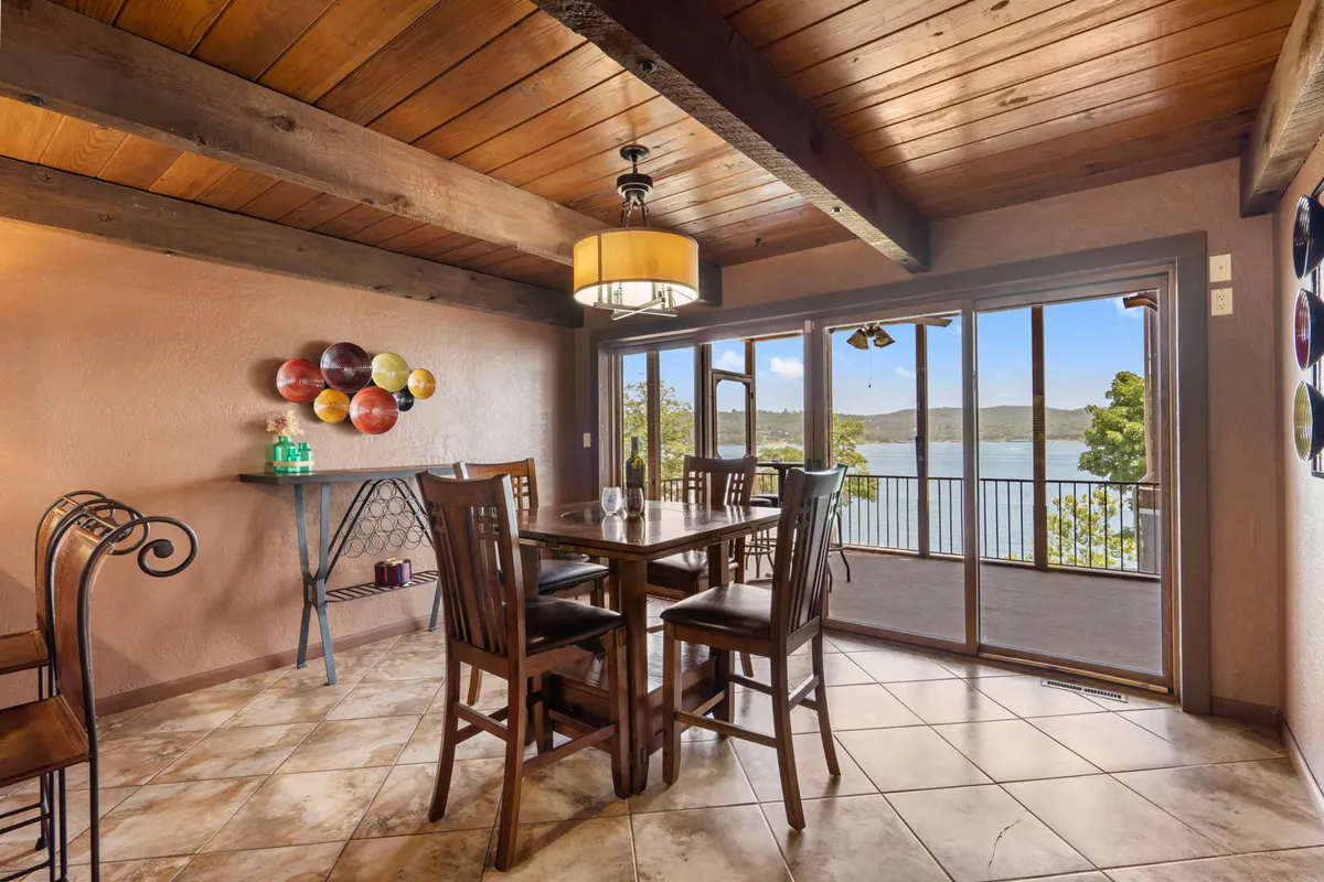 A bright, cozy dining room with a wooden dining table, colorful artwork, and expansive glass doors that open to a scenic lake view. This setting is ideal for both everyday meals and special celebrations, complimenting the narrative of memorable gatherings.