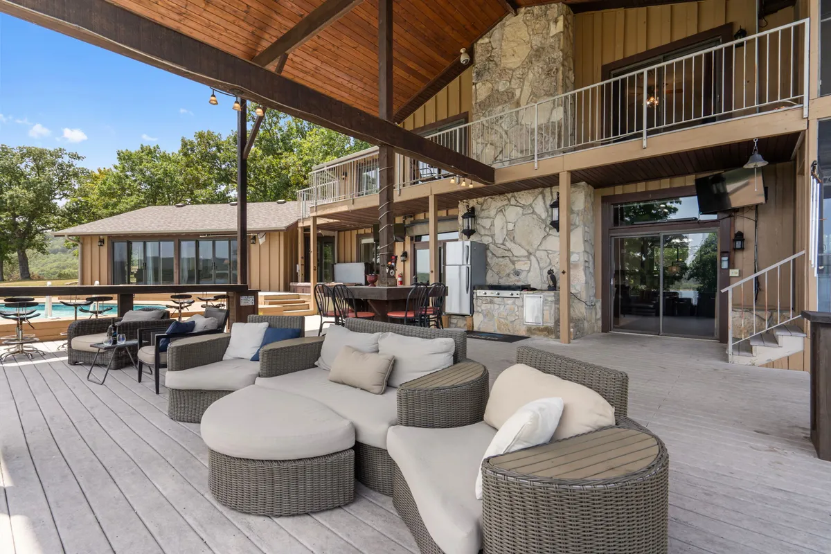 A welcoming outdoor lounge area with a fireplace, seating, and a swimming pool in the background, surrounded by lush trees. The space is ideal for relaxing, grilling, or sharing stories after a day on the water.